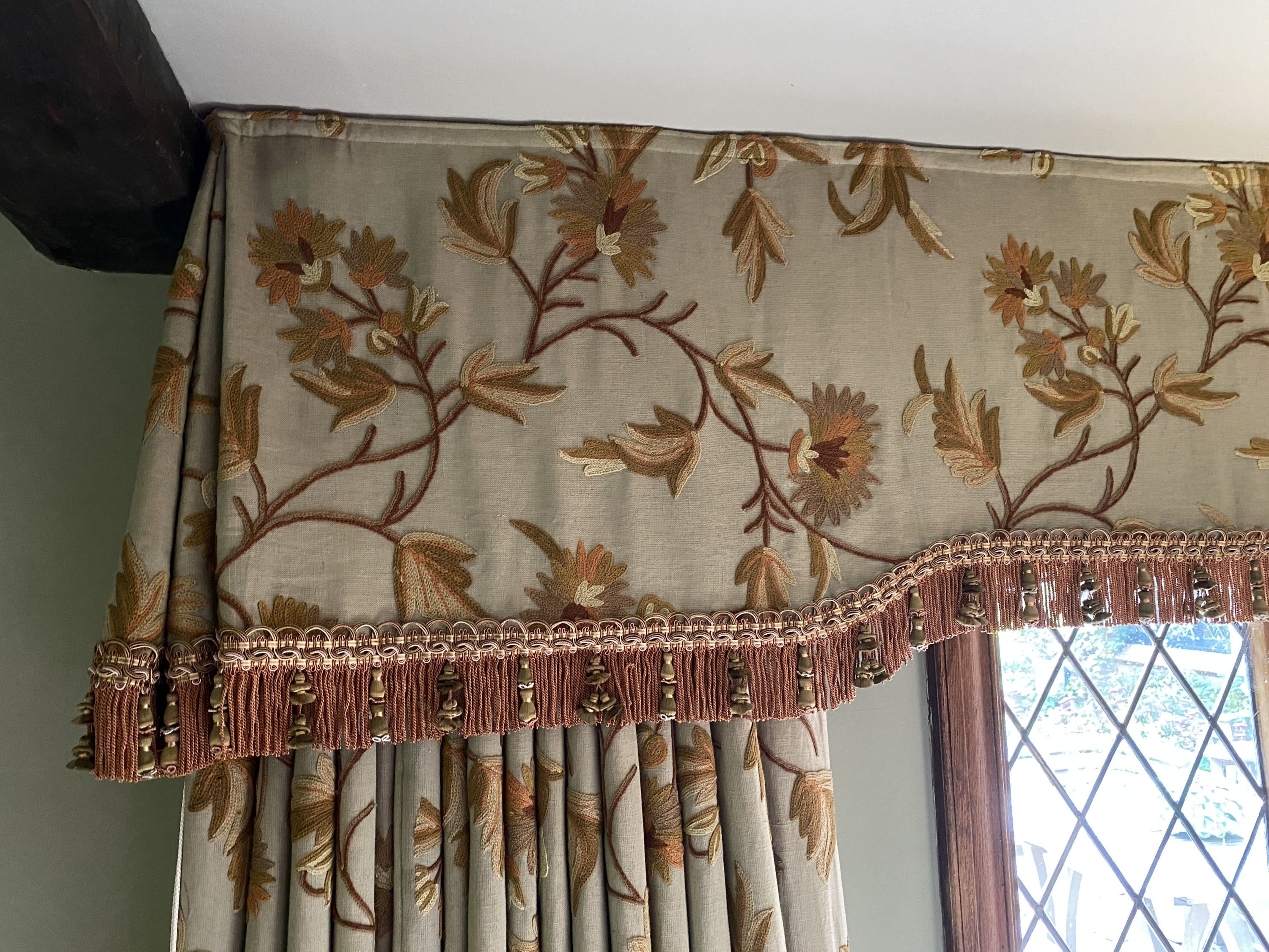 A pair of eau de nil linen curtains with floral crewel work decoration, and matching two piece pelmet, drop 230cm, generously made to fit an aperture of 3.8m
